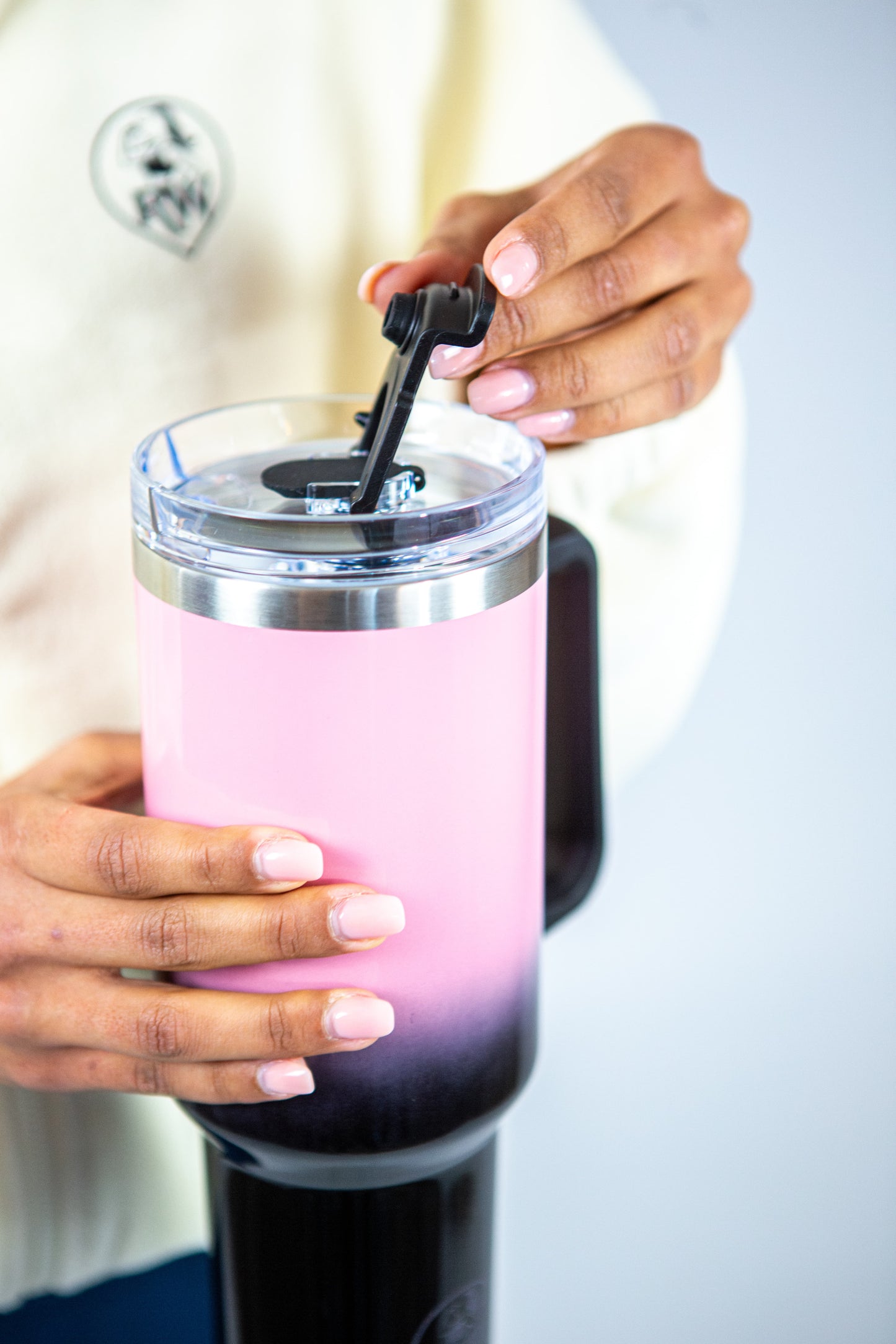 femme tenant la gourde rose et noir reveal wear et montrant le couvercle
