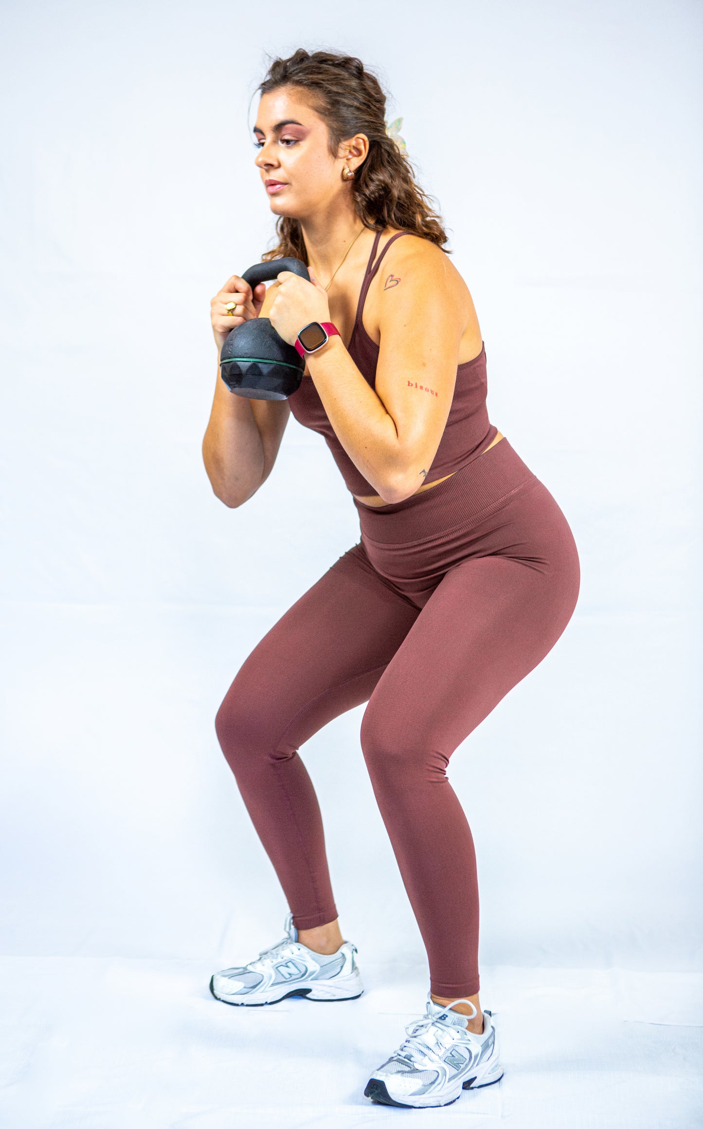 femme en tenue reveal wear cacao avec un poids libre dans les mains s'apprêtant à faire un squat