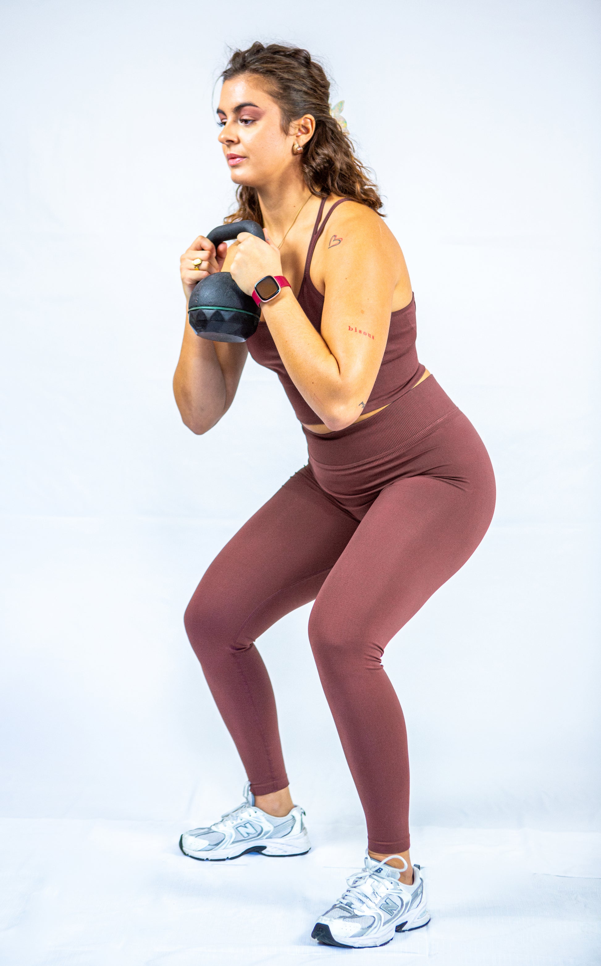 femme en tenue reveal wear cacao avec un poids libre dans les mains s'apprêtant à faire un squat